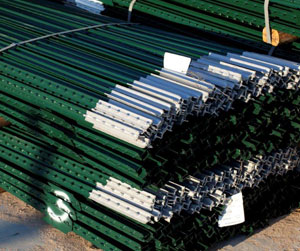 A large stack of green and white metal fence posts painted with Trinkote dipping enamel.